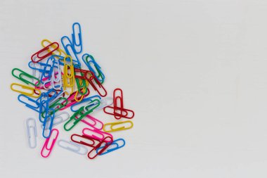 Birçok renkli ataç beyaz ahşap bir masanın üzerinde yatıyor. Metin için yeri olan arkaplan.