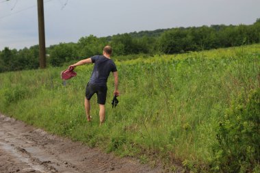 Bir köylü yağmurdan sonra ıslak toprak bir yolda evine dönmeye çalışıyor. Yol eksikliği.