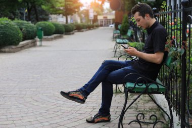 Şehir ortamının bulanık arka planında günlük kıyafetlerle gezen beyaz bir gencin yaşam tarzı portresi..