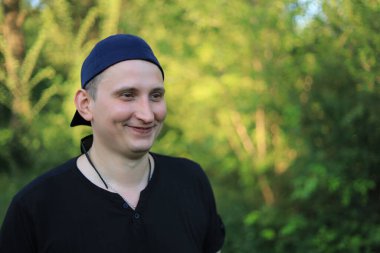 Sıradan giyinen beyaz bir genç ya da yetişkin bir erkek yeşil bir parkta doğayla bütünleşmekten zevk alır. Mutluluk ve özgürlük kavramı. Yaşam biçimi, tonlu arkaplan