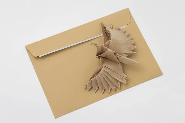 Origami paper bird mockup. Selective focus. Against the background of a classic mail envelope.