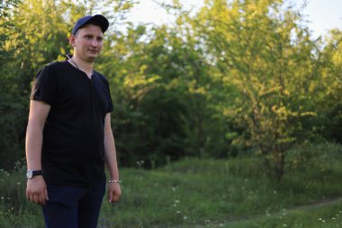 Beyaz genç adam ya da yetişkin adam parkta yürür. Ayarlanmış arkaplan.