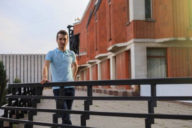 Şehir ortamının bulanık arka planında günlük giysiler içinde genç bir beyaz adamın yaşam tarzı portresi..