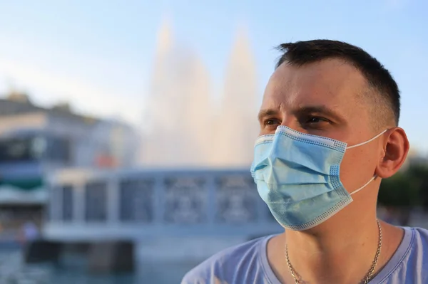 Mutlu gülümseyen genç turist günlük giysiler içinde ve tıbbi bir maske takarak covid-19 salgını sırasında yüzünü koruyor..