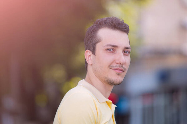 Lifestyle portrait of a young Caucasian man in casual wear on a blurred background of the urban environment.