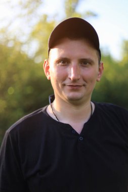 Sıradan giyinen beyaz bir genç ya da yetişkin bir erkek yeşil bir parkta doğayla bütünleşmekten zevk alır. Mutluluk ve özgürlük kavramı. Yaşam biçimi, tonlu arkaplan