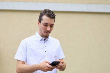 Şehir ortamının bulanık arka planında günlük giysiler içinde genç bir beyaz adamın yaşam tarzı portresi..