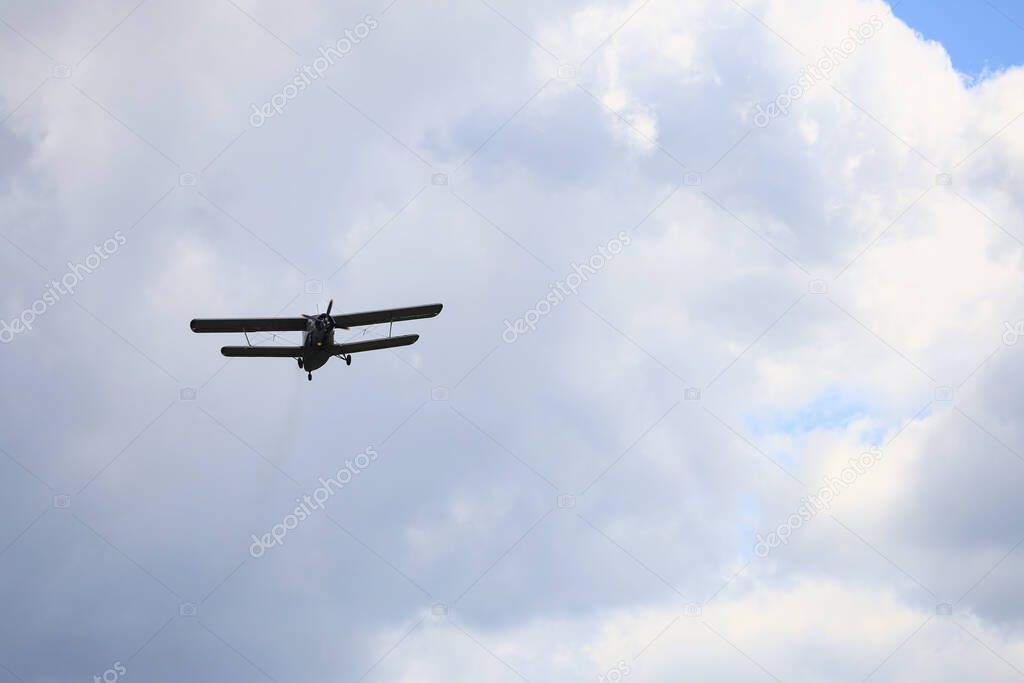 Classic old retro vintage airplane with a propeller in the sky on a background of clouds.