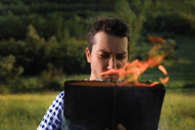 Beyaz Kafkas genci ya da yetişkin bir adam bulanık orman geçmişi hakkında yanan bir kitap okuyor. Ciddi bir gerilim hissi..