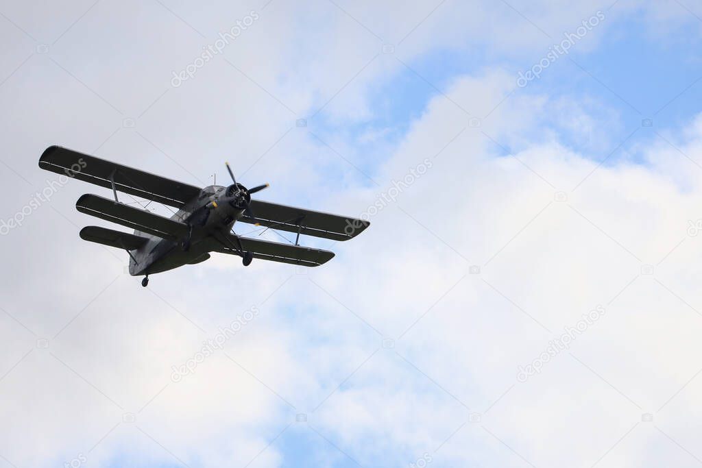 Classic old retro vintage airplane with a propeller in the sky on a background of clouds.