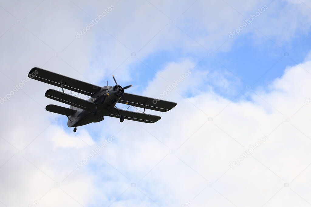 Classic old retro vintage airplane with a propeller in the sky on a background of clouds.