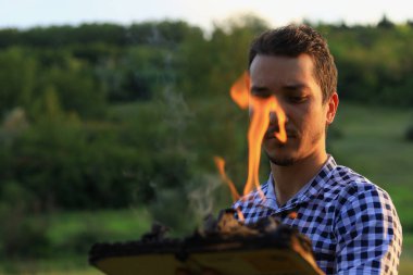 Beyaz Kafkasyalı genç adam ya da yetişkin adam bulanık orman geçmişi üzerine yanan bir kitap okuyor..