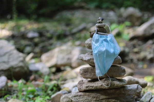 The medical surgical mask covers the pyramid of stones. Selective focus. The concept of travel and hiking during a pandemic.