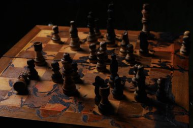 Karanlıkta yanmış satranç taşları. Seçici odaklanma. Sanatsal tasarımda anksiyete ve gerilim yaratmak için yanlış kompozisyon.