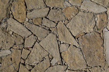 Vahşi dekoratif süsleme taşından yapılmış pürüzlü bir duvar. Sert ve zıt ışıkla arkaplan.