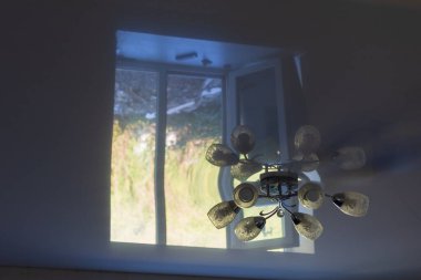 Uzamış beyaz bir tavandaki avizenin dışında odanın karanlığında bir ışık penceresinin yansıması. Kopyalama alanı olan arkaplan