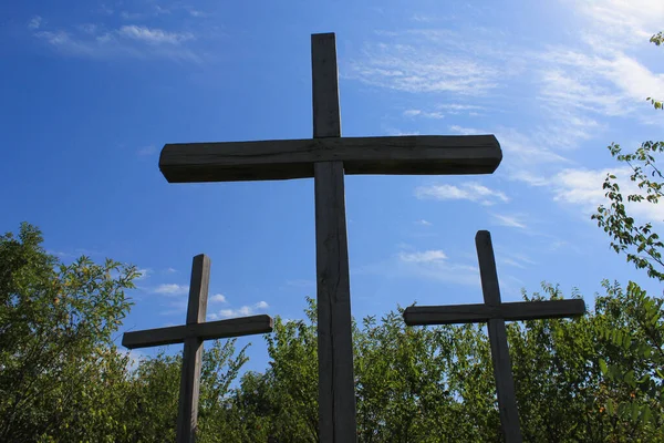 Silhouettes of old wooden crosses in contrasting sunlight. A pilgrimage site on a mountain in the forest. Religious travel to holy places, abstract background