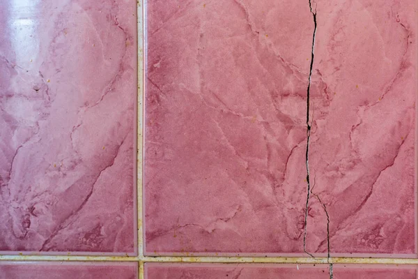 Cracked tiles on the wall of an emergency house. Shrinkage of the foundation. Landslide or earthquake