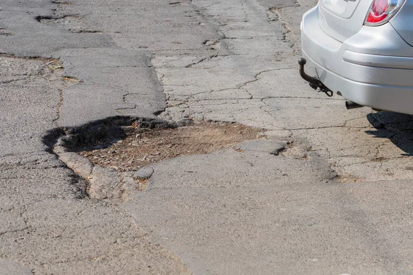 Very bad bumpy road. A worn-out asphalt bed. Illustrative background for editorial news. An urgent need for overhaul