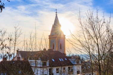 Huzurlu Avrupa köyü manzarasında güneş ışığı alan kilise kulesi.