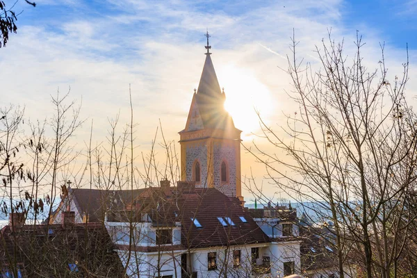 Huzurlu Avrupa köyü manzarasında güneş ışığı alan kilise kulesi.