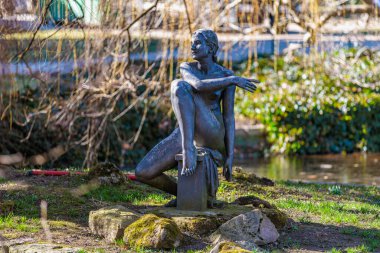Parkta oturan kadının bronz heykeli. 19 Mart 2025, Karlovy Vary, Çek Cumhuriyeti.