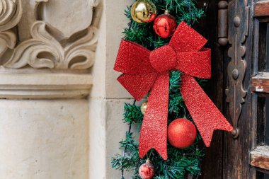 Kapısında kırmızı fiyonk ve noel süsleri olan bayram dekoru..