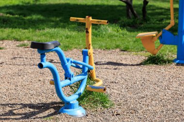 Güneşli parktaki çakıl üzerinde açık hava egzersiz ekipmanları.