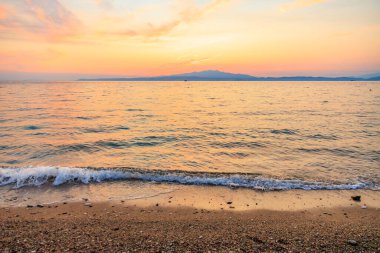 Okyanus sakin ve gökyüzü güzel turuncu bir renktir. Güneş batıyor, huzurlu ve huzurlu bir atmosfer yaratıyor.