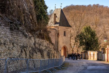 İnsanların dağ yolunda yürüdüğü tarihi bir taş yapı. 19 Mart 2025, Karlstejn, Çek Cumhuriyeti.