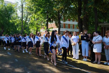Açık havada mezuniyet töreni: akademik başarıyı resmi kıyafetle kutlayan genç yetişkinler. 31 Mayıs 2024 Balti Moldova.