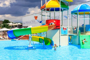 Su kaydırağı ve su sıçrama tahtası olan bir çocuk parkı. Kaydırak renkli ve sıçrama yastığı mavi. 8 Haziran 2024 Balti Moldova