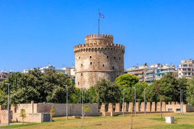 Üzerinde mavi ve beyaz bayrak olan uzun bir kule. Gökyüzü açık ve mavi. Kule ağaçlar ve binalarla çevrilidir. 8 Ağustos 2024 Selanik Yunanistan