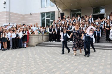 Coşkulu kalabalığın önünde 16 işaret taşıyan çocukların olduğu okul kutlaması. 2 Eylül 2024 Balti Moldova.