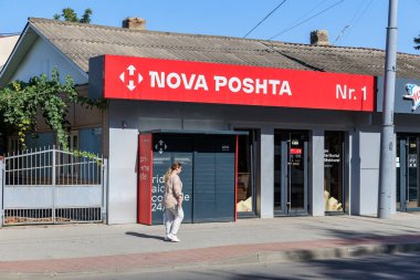 Nova Posta Ofisi 'nin dış tarafında güneşli bir günde yürüyen yetişkin bir kadın var. 9 Eylül 2024 Balti Moldova.