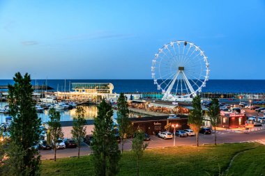 Dönme dolap ve deniz kenarındaki yat limanının akşam manzarası. 3 Mayıs 2025 Romanya.