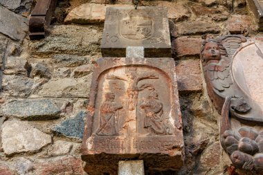 Tarihi tuğla duvarlara dini semboller ve melek heykelleri kazınmış antik taş oymalar. 17 Mart 2025, Konopiste Şatosu, Çek Cumhuriyeti.