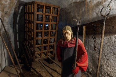 Yaşlı erkek figürü ve işkence aletleriyle ortaçağ zindan sahnesi. 18 Mart 2025, Madalyon, Çek Cumhuriyeti.