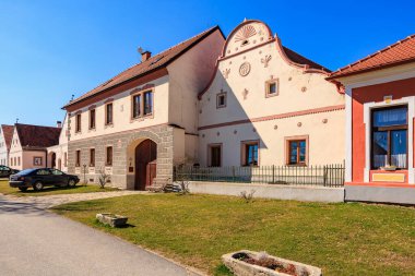 Güneşli bir günde dekoratif görünüşlü tarihi köy evi. 21 Mart 2025, Holasovice, Çek.