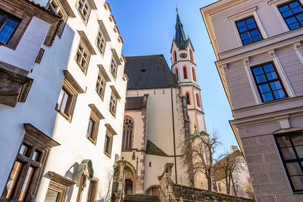 Güneşli bir günde Cesky Krumlov 'daki Gotik kilise ve tarihi binalar. 20 Mart 2025, Cesky Krumlov, Çek.