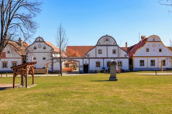 Açık mavi gökyüzü altında geleneksel beyaz evleri olan tarihi barok köyü. 21 Mart 2025, Holasovice, Çek.