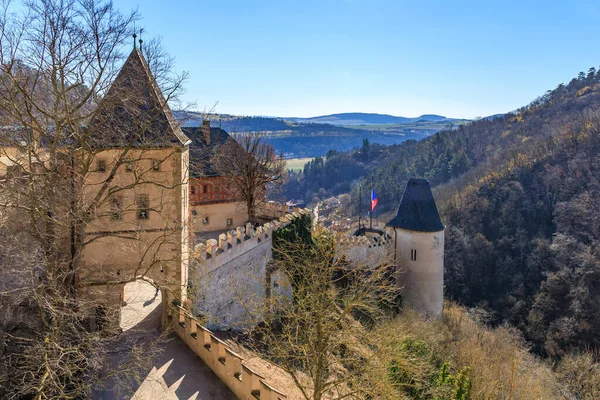Ortaçağ kale kuleleri ormanlı tepeler ve açık mavi gökyüzü arasında.
