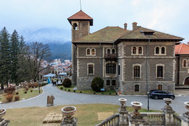 Önünde bir çan kulesi ve bir araba olan büyük bir bina. 15 Aralık 2024 Busteni Romanya.