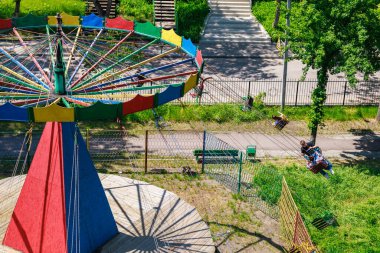 Boş koltukları ve hareket bulanıklığıyla güneşli parkta renkli bir gezinti. 22 Mayıs 2025 Balti Moldova.