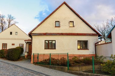 Sessiz yerleşim yerlerinde çatısı ve kaldırım taşı yolu olan büyüleyici beyaz bir ev. 17 Mart 2025, Benesov, Çek Cumhuriyeti.