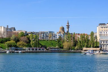 Şehir binalarının manzarası ve mavi gökyüzüne karşı cami manzarası. 3 Mayıs 2025 Romanya.
