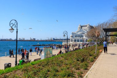 Güneşli bir günde deniz kenarında insanlarla ve tarihi binalarla gezinti. 3 Mayıs 2025 Romanya.