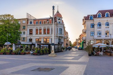 Günbatımında tarihi binalar ve açık hava oturma yerleriyle Avrupa meydanını büyülüyor. 3 Mayıs 2025 Romanya.