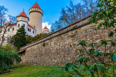 Taştan duvarları ve yemyeşil manzaralı kırmızı çatı kuleleri olan ortaçağ şatosu.