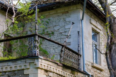 Terk edilmiş, sarmaşıklı ve yıpranmış balkonlu taş bir ev..